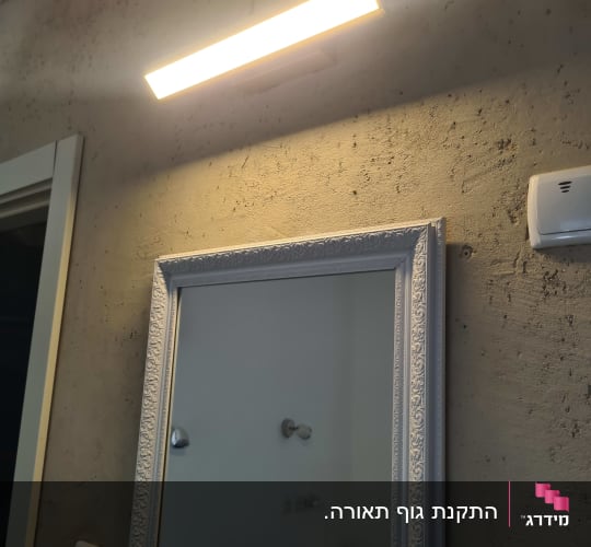 מנורה מותקנת מעל מראה על קיר